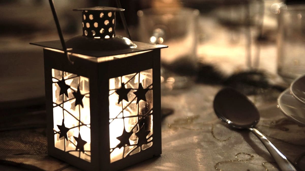 Lanterne allumée posée sur une table, dans une pièce sombre