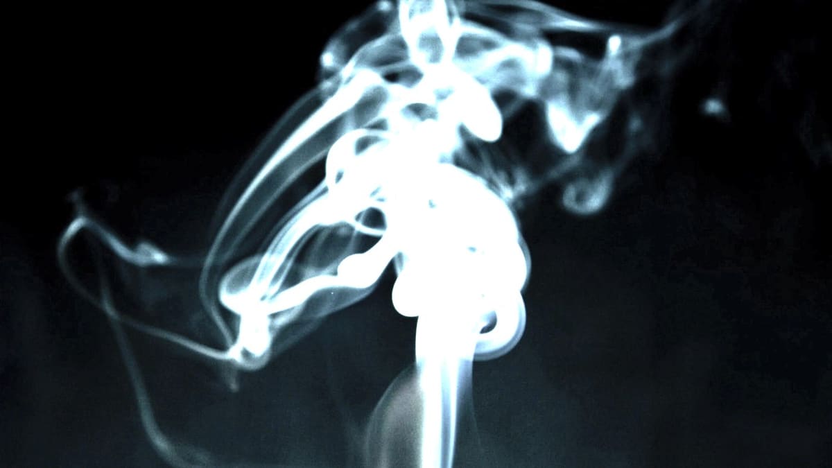 Volutes de fumée d'encens s'élevant dans l'obscurité